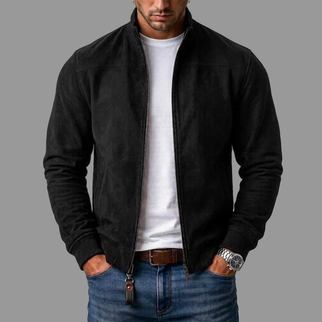 Model draagt de zwarte jack open over een wit T-shirt en spijkerbroek, met een leren sleutelhanger aan de rits. 1