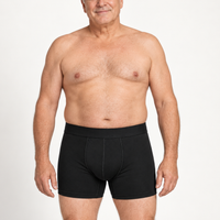 Oudere man met grijs haar draagt de zwarte boxershort, getoond van voren in staande houding tegen een witte achtergrond. 2