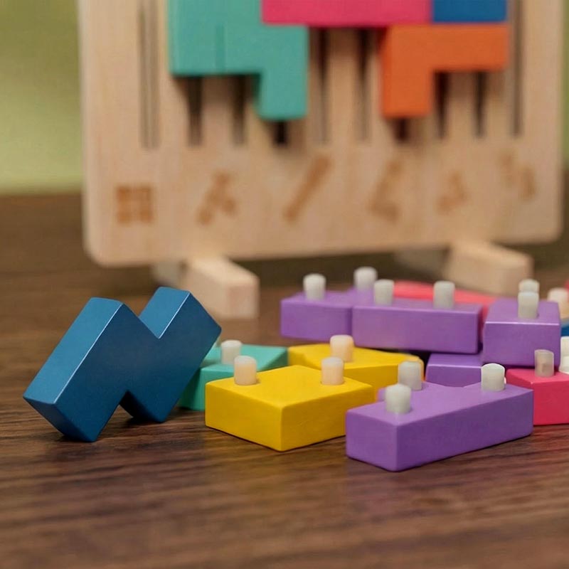 Close-up van losse gekleurde blokken met kleine witte pennetjes, met op de achtergrond het houten bord met ingebrande vormen. 5
