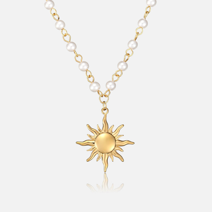 Voorkant van de ketting met witte parels aan gouden schakels en een gouden zonhanger met golvende stralen op een lichte achtergrond. 1