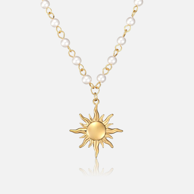 Voorkant van de ketting met witte parels aan gouden schakels en een gouden zonhanger met golvende stralen op een lichte achtergrond. 1