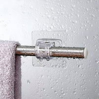Metalen handdoekstang in een doorzichtige klem aan een vochtige, met waterdruppels bedekte tegelwand, met een lila handdoek eroverheen. 4