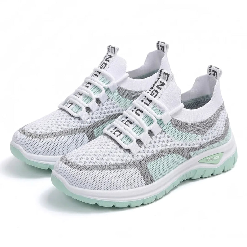 Twee witte gaas sneakers met mintgroene zool en grijze accenten, schuin van voren, met elastische veterlussen. 16