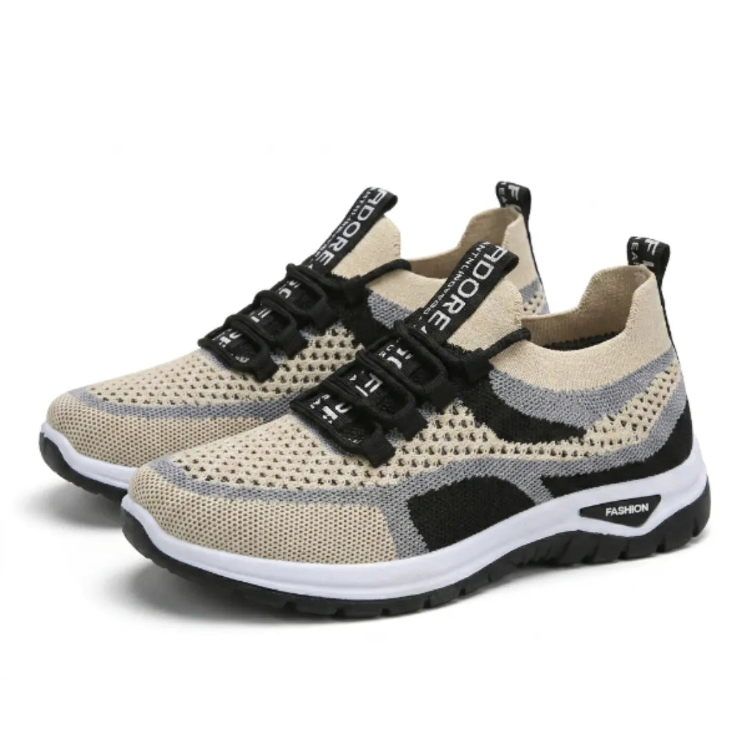 Paar beige sneakers met grijze en zwarte accenten, zwarte veters en witte zool, schuin van voren gezien. 43