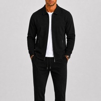 Model draagt de set in zwart met wafelstructuur, jack open over wit shirt, handen in zakken 3