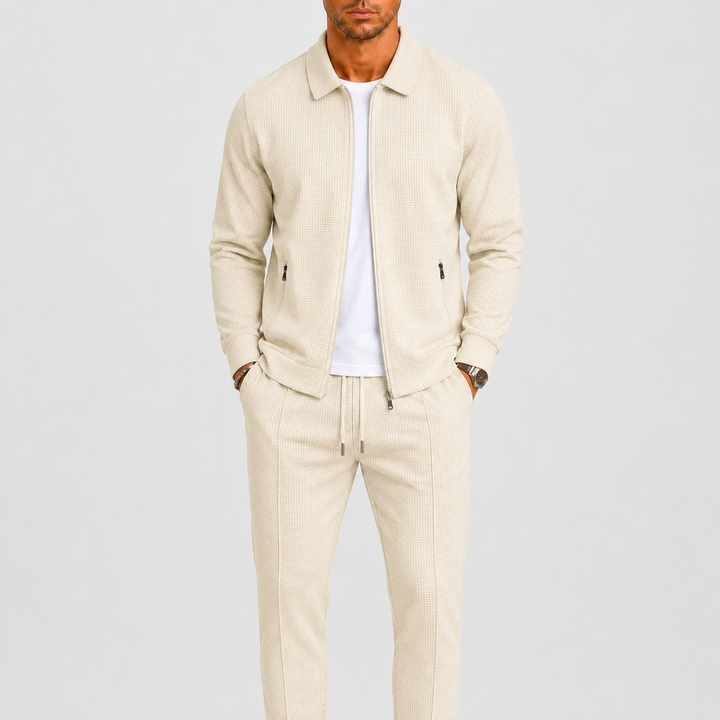 Model draagt de set in crèmebeige met wafelstructuur, open jack over wit shirt, handen in zakken 1