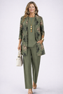 Model in olijfgroene set met vest met bladerprint, effen top en wijde broek, met witte tas 1