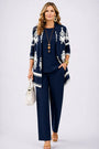 Model in marineblauwe set met wit sierpatroon op het open vest, effen top en broek 7