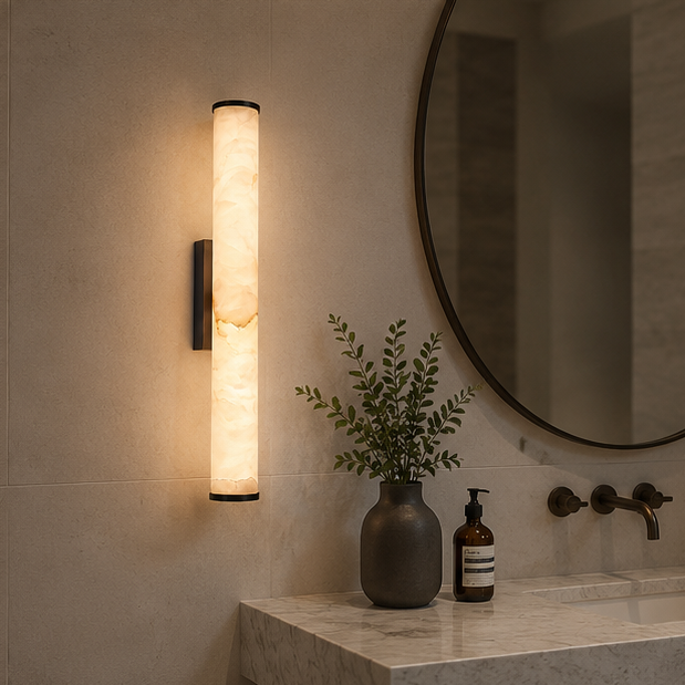 Wandlamp met gemarmerde cilinder en donkere uiteinden in een badkamer, naast een ronde spiegel, wastafel en zeepdispenser. 4
