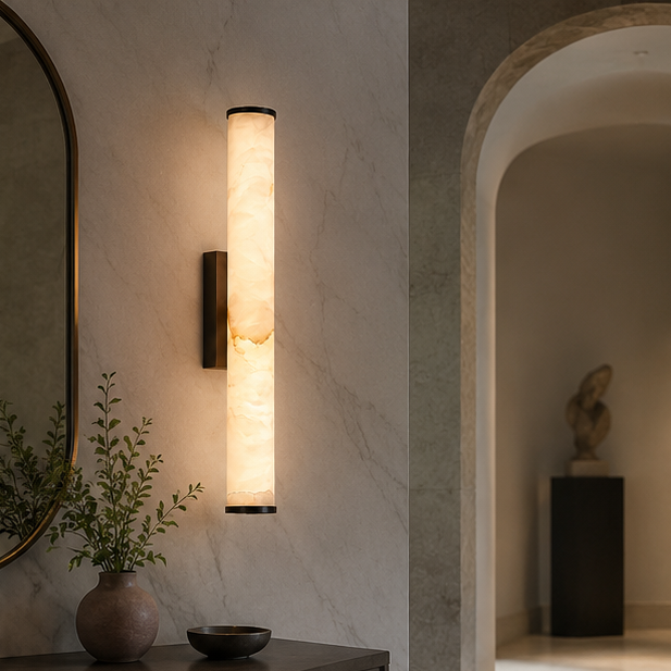 Verlichte marmeren wandlamp op een gemarmerde muur in een hal met boog, naast een spiegel en een vaas met takje. 5