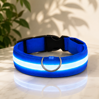 Blauwe halsband van geweven nylon met oplichtende witblauwe led-strook, metalen D-ring en zwarte clipsluiting, op een marmeren tafel. 1