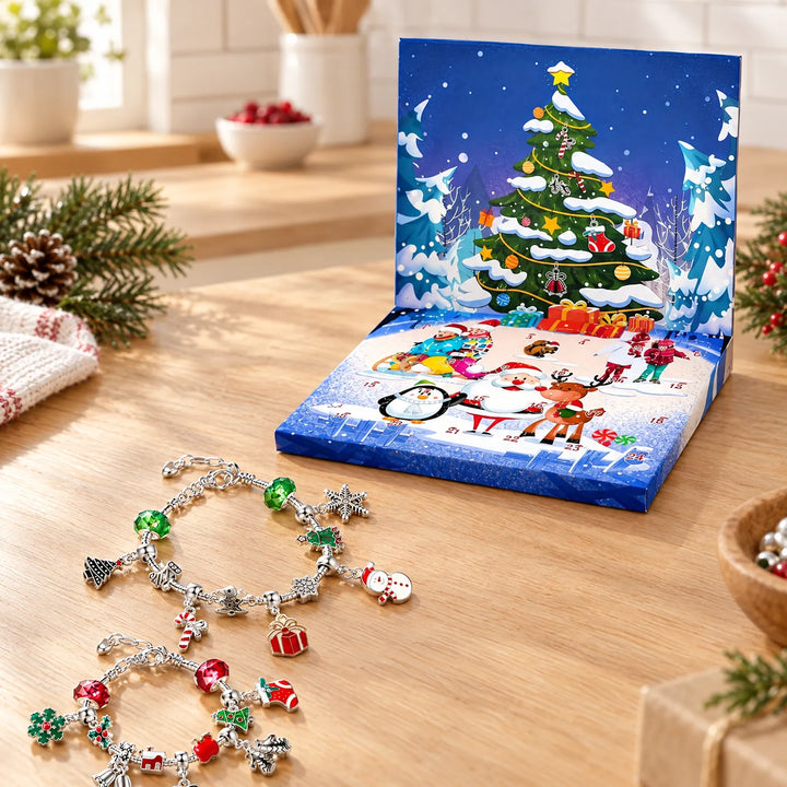 Twee bedelarmbanden met kerstbedels naast een opengeklapte blauwe adventskalenderdoos met kerstboom, op een houten tafel met dennentakken. 1