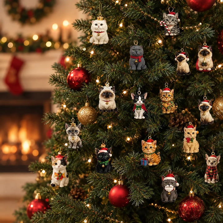 Kleine kattenhangers in kerstkleding opgehangen aan een verlichte kerstboom met rode en gouden kerstballen, met een open haard op de achtergrond. 1