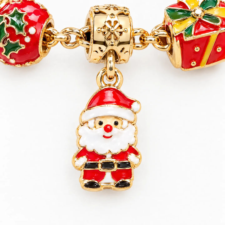 Close-up van een gouden kerstmanbedel in rode en witte emaille, tussen een hulstbedel en een rood cadeaubedel aan een armband. 3