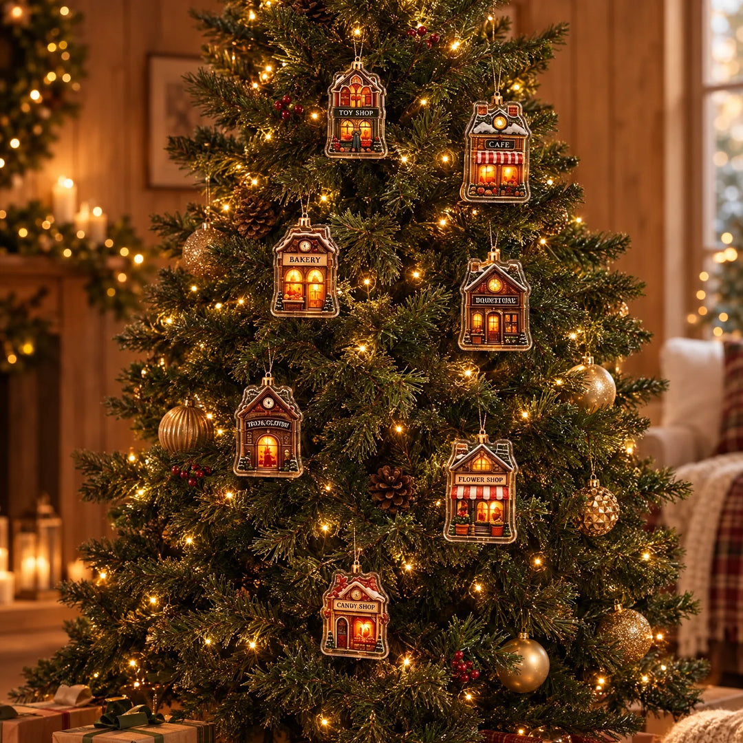 Zeven kleine doorzichtige huisjes als ornamenten opgehangen in een verlichte kerstboom met gouden kerstballen in een warme woonkamer. 1