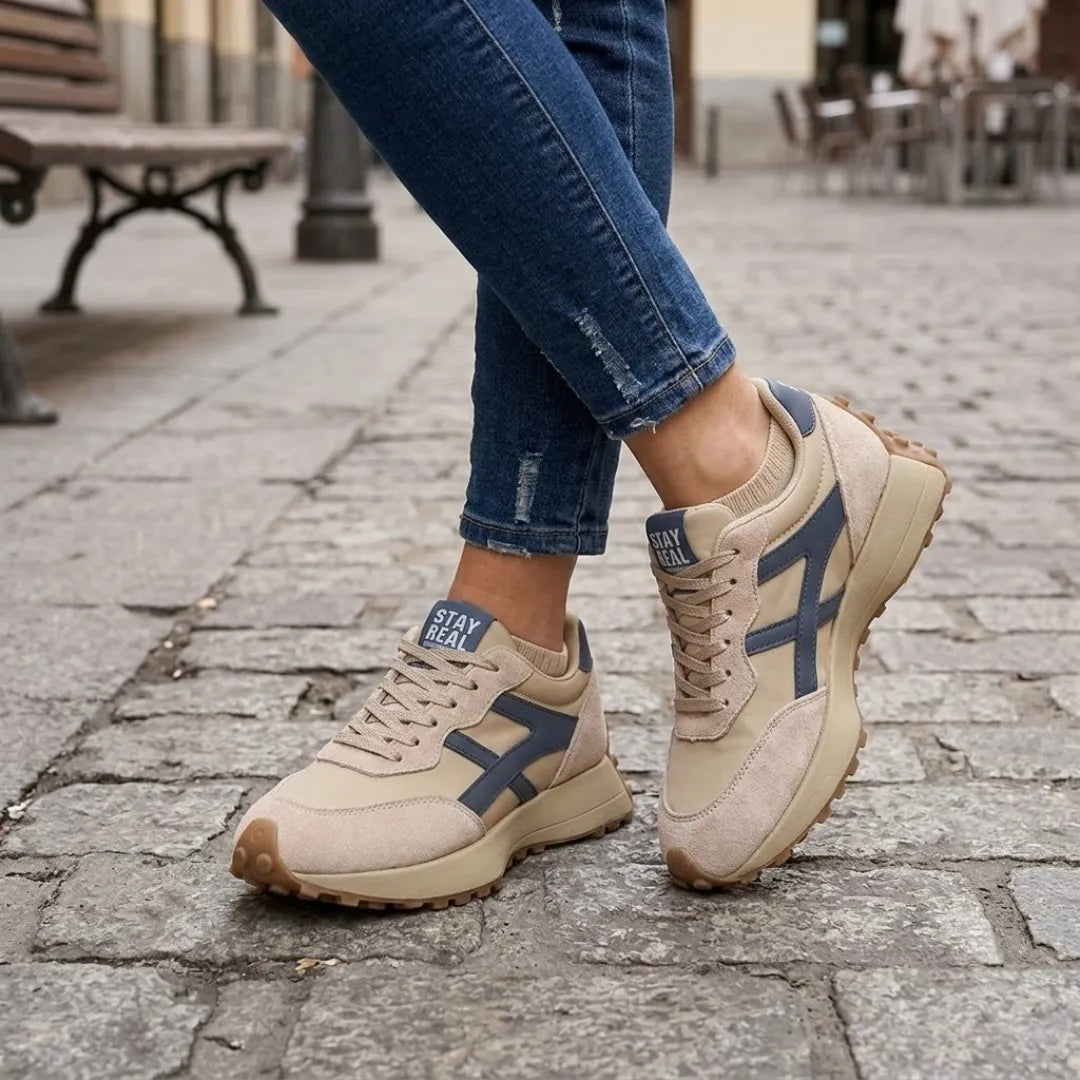 Beige sneakers met blauwe details gedragen met jeans op een kinderkoppenstraat 2
