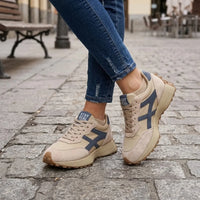 Beige sneakers met blauwe details gedragen met jeans op een kinderkoppenstraat 2
