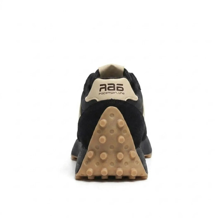 Zwarte sneaker van achteren, met beige hielstrook en driehoekige bruine noppenzool 20