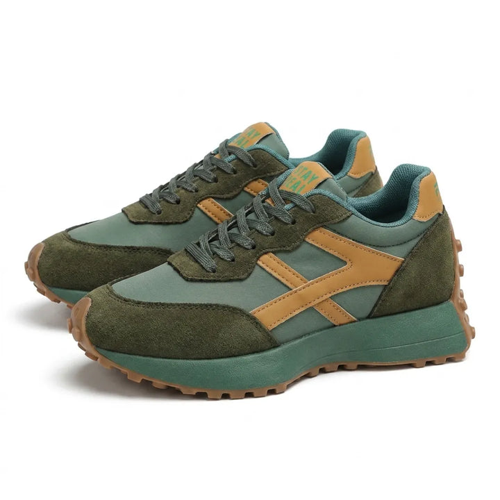 Paar groene sneakers met okergele strepen en veters, schuin vooraanzicht op witte achtergrond 13