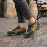 Groene sneakers met okergele details gedragen met grijze pantalon op een straat 12