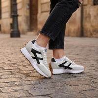 Sneakers gedragen door een model met zwarte jeans en witte sokken op een stenen straat 22