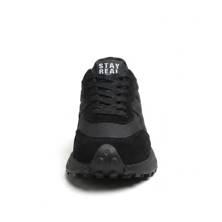 Zwarte sneaker van voren, met geveterde sluiting en noppen onder de neus 9