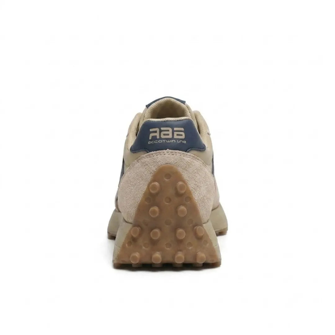 Beige sneaker van achteren, met blauwe hielstrook en driehoekige zool met noppen 5