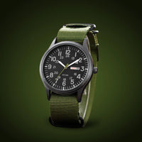 Schuin gefotografeerd horloge met legergroene geweven band en zwarte wijzerplaat tegen een donkergroene achtergrond. 4