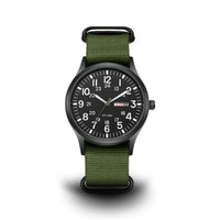 Vooraanzicht van het horloge met zwarte wijzerplaat, 24-uurs cijfers, dag-datumvenster en legergroene geweven band met zwarte ringen. 1