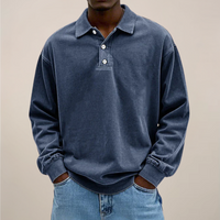 Model draagt de losse polo met lange mouwen en knoopsluiting in donkerblauw, met handen in de zakken van een spijkerbroek. 5