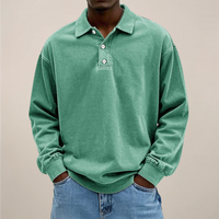 Model draagt de losse polo met lange mouwen en knoopsluiting in mintgroen, met handen in de zakken van een spijkerbroek. 9