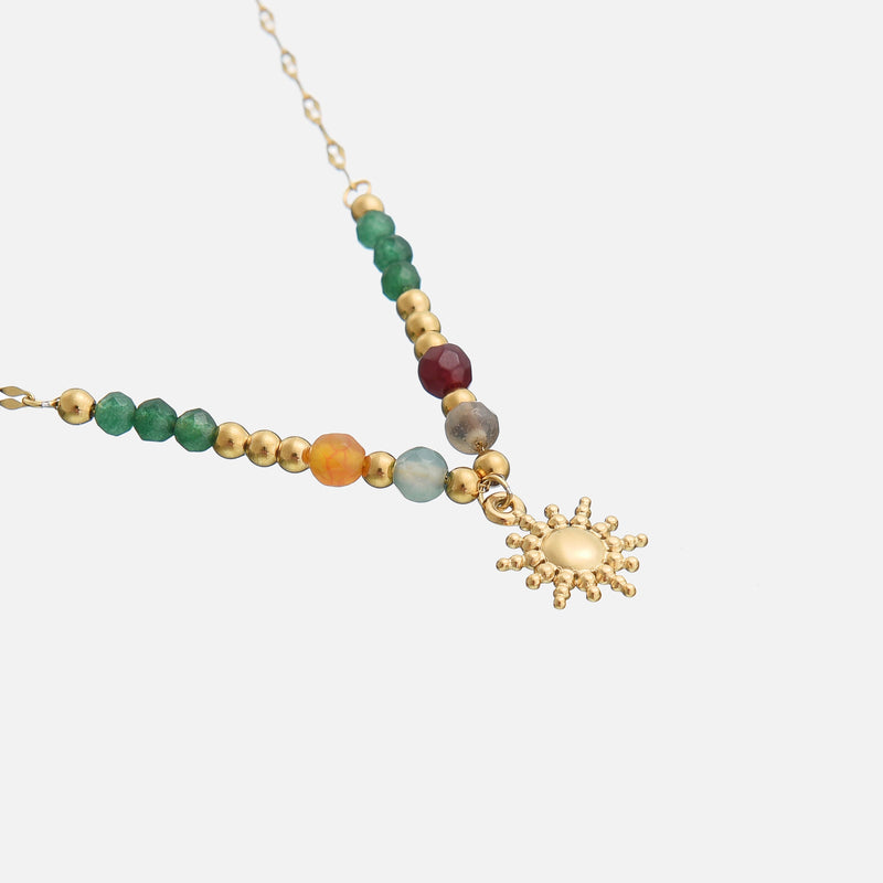 Gouden kralenketting met zonnehanger, schuin van boven bekeken op een lichte achtergrond 2