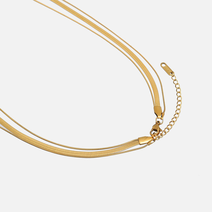 Close-up van de karabijnsluiting en het verlengkettinkje van de gouden gelaagde ketting op een lichte ondergrond 2