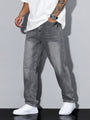 Grijze washed jeans gedragen door een model in wit t-shirt en witte sneakers, schuin van voren met hand in de zak. 1