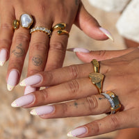 Twee handen met gelakte nagels waarop de ring gecombineerd is met andere gouden ringen 4
