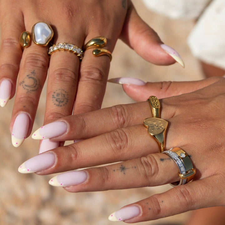 Twee handen met gelakte nagels waarop de ring gecombineerd is met andere gouden ringen 4