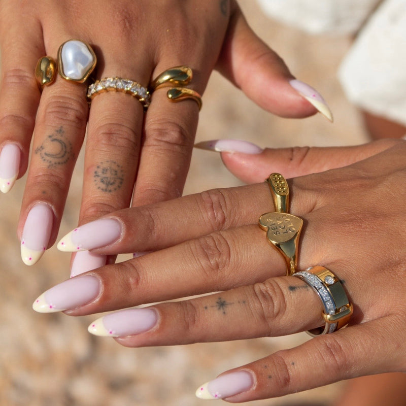 Twee handen met gelakte nagels waarop de ring gecombineerd is met andere gouden ringen 4