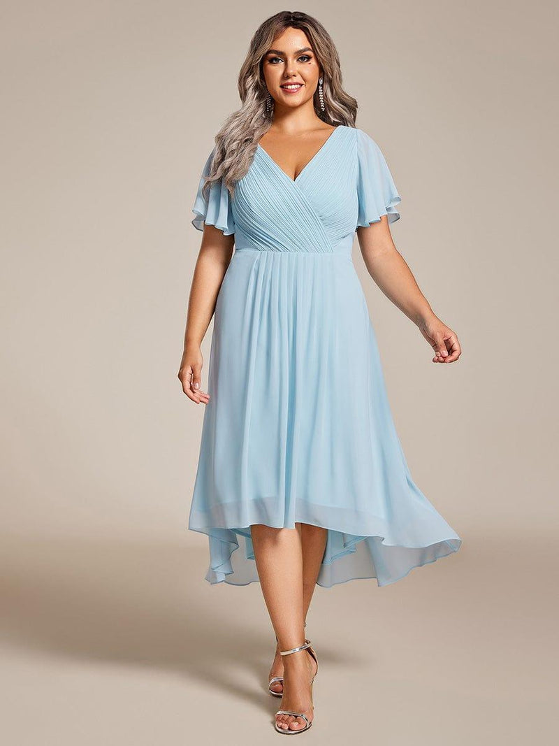 Model met ruimere maat in lichtblauwe chiffon jurk met V-hals, fladdermouwen en hoog-laag zoom, zilveren sandalen. 89