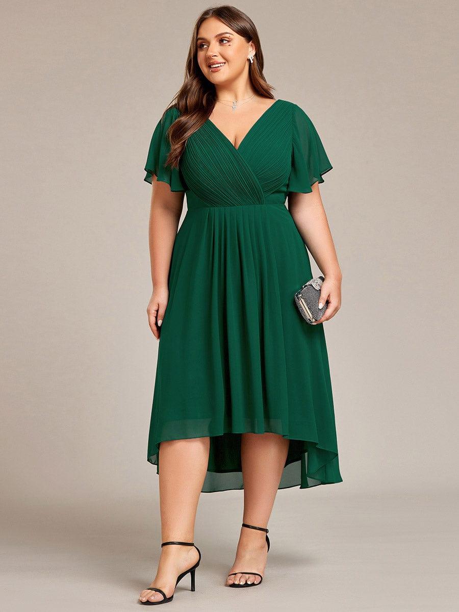 Donkergroene jurk in grotere maat van voren, model draagt een glinsterende clutch en zwarte sandalen. 40