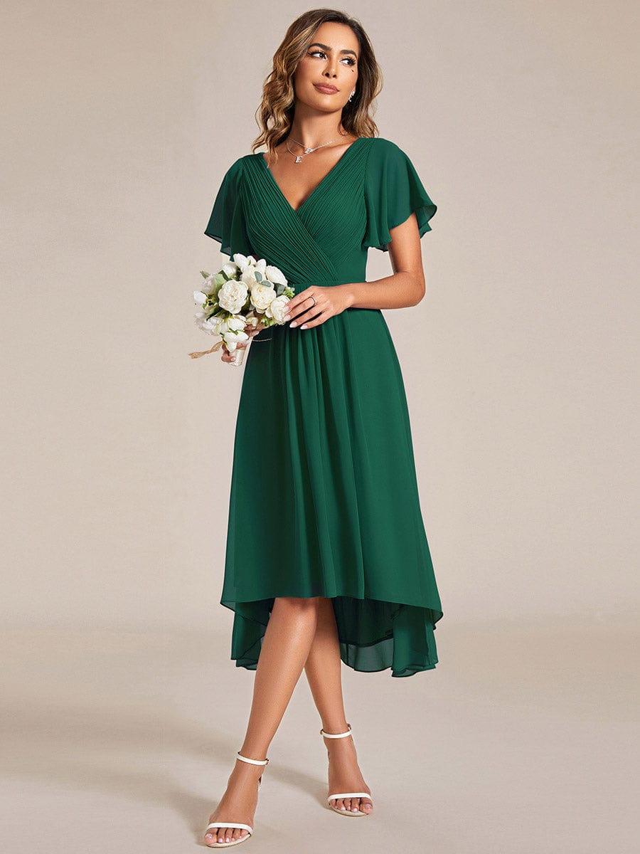 Donkergroene jurk gedragen met een klein boeket witte bloemen, schuin van voren, met chiffon zoom 13