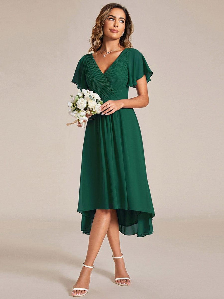 Donkergroene jurk gedragen met een klein boeket witte bloemen, schuin van voren, met chiffon zoom 13