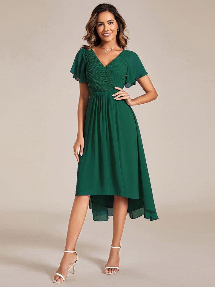 Donkergroene jurk met gedrapeerd lijfje, vlindermouwen en asymmetrische zoom, model met hand op de heup, voorkant 10