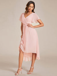 Roze jurk schuin van voren, model tilt de wijde chiffon rok licht op en toont de asymmetrische zoom 19