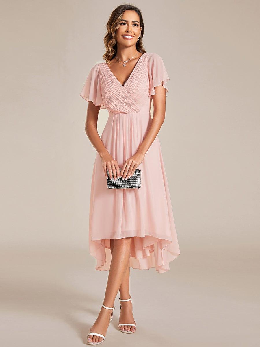 Roze jurk met gedrapeerde V-hals en vlindermouwen, gedragen met zwart clutchtasje en witte sandalen, voorkant 15