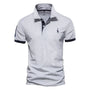 Lichtgrijs poloshirt met donkerblauwe mouwboorden en knoopstrook, een geborduurde giraf en een nummer op de mouw 4