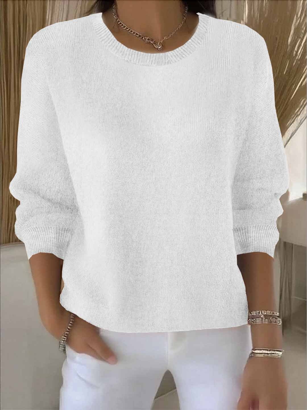 Witte gebreide trui met ronde hals, gedragen door een model met sieraden en een witte broek 3