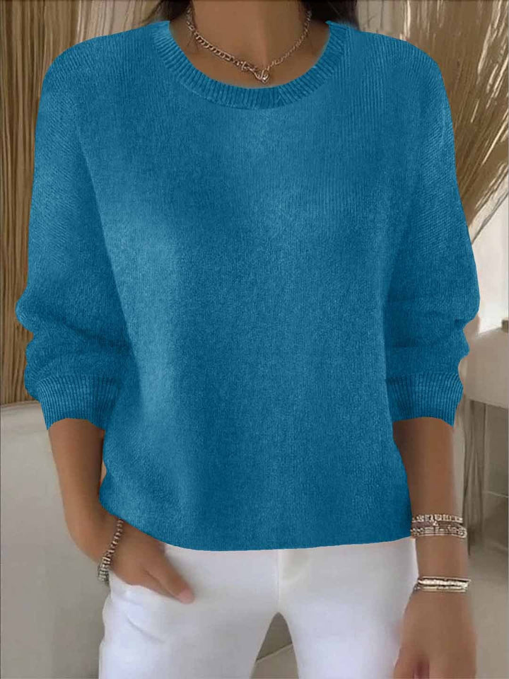 Turquoiseblauwe gebreide trui met ribboord, gedragen door een model met een witte broek 12