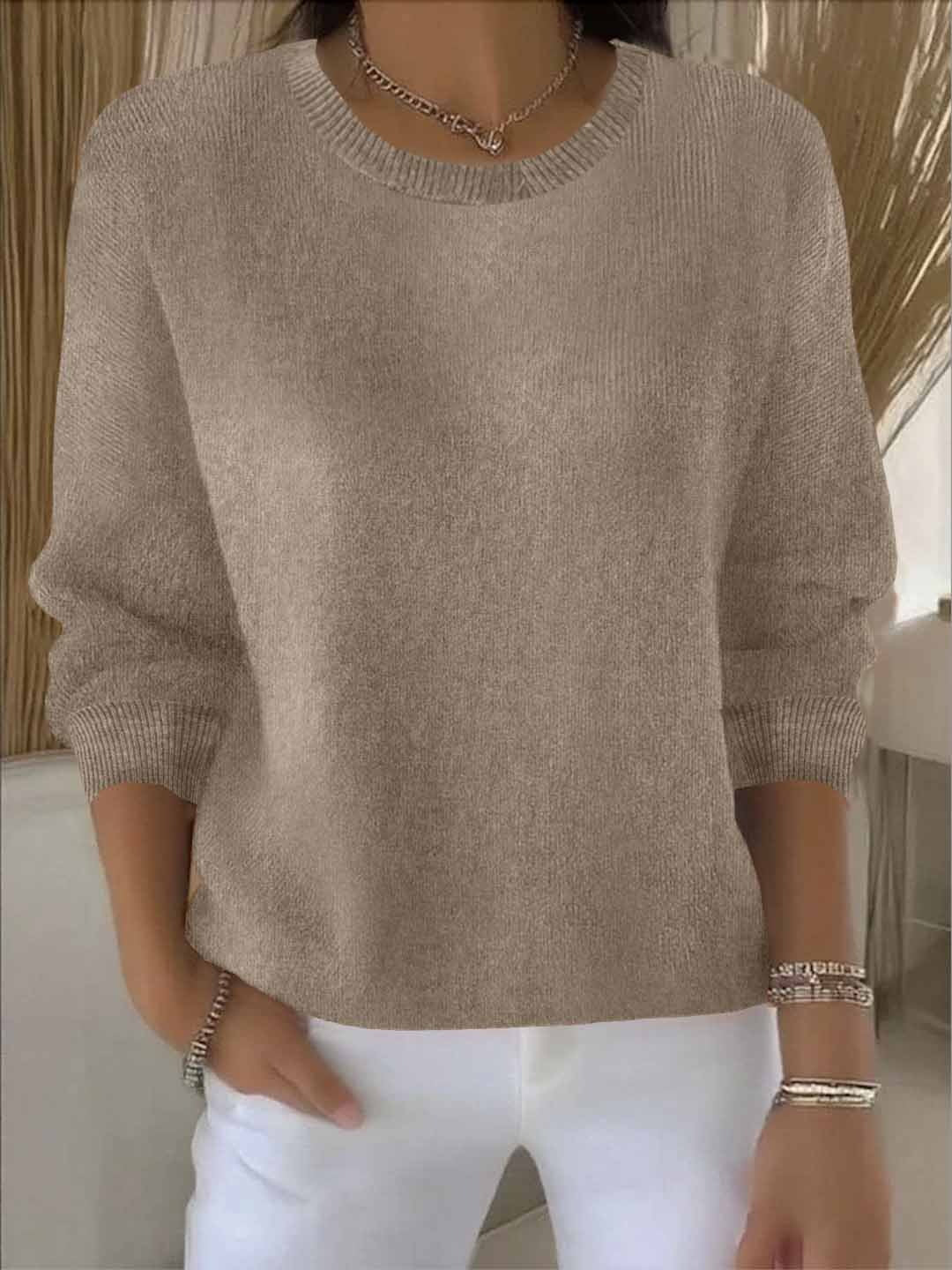Taupe gebreide trui met ronde hals, gedragen door een model met een witte broek en armbanden 5