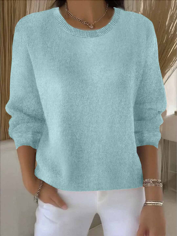 Lichtblauwe gebreide trui in zachte tint, gedragen door een model met een witte broek en armbanden 10