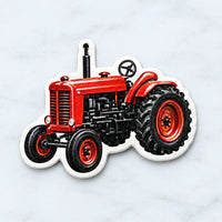 Close-up van een los ornament in de vorm van een rode tractor met wit randje en een gaatje om op te hangen. 3